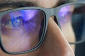 Man looks at computer screen which is reflected in his glasses