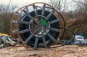 Steel roller with fiber optic cables for the installation of data cables on a construction site.