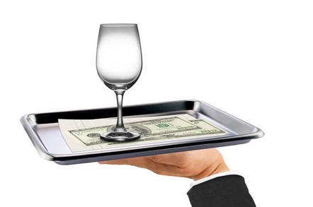 A wine glass and some money on a silver platter