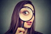 Curious woman looking through a magnifying glass