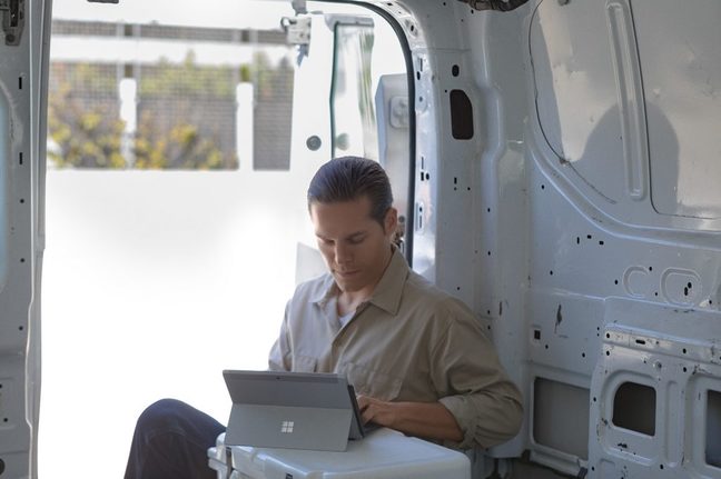 Man in white van using a Surface Go