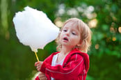 Little girl eating cotton candy in the park