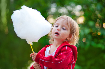 Little girl eating cotton candy in the park