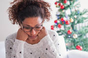 woman looks pensive in front of a christmas tree