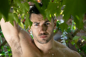 Shirtless man under rain shower in garden