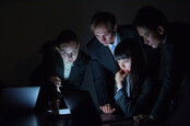 group of people in suits look at laptop screens