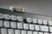 Figures of workers have a coffee break on a keyboard