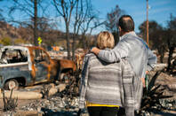 A couple stare at their wrecked home