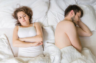 oung man is sleeping in bed. Sad, disappointed and unsatisfied girlfriend lying near