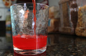 Pouring red drink into glass