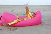 man in gold suit on beach lies on gold pillow