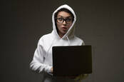 Someone in a white hoodie holding a laptop