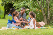 Cheerful family sitting on the grass during a picnic in a park