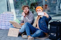 Two homeless men with a phone