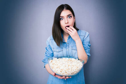 A woman eating popcorn in shock