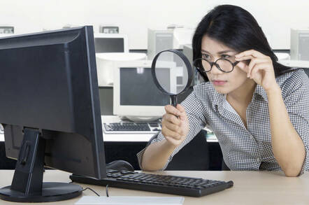 Woman peering at something in her office using a magnifying glass