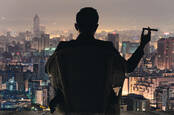 Generic rich guy looking over a nice city night-time view with a cigar