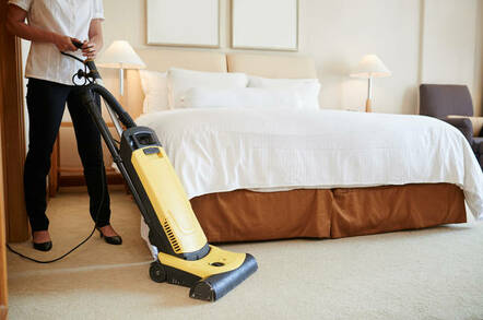 Maid cleaning carpet in hotel room