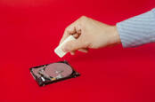 A hand holding an eraser on a hard drive