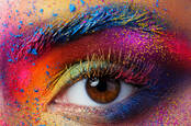 A human eye surrounded by colorful face paint