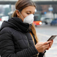 Someone in a mask using a COVID-19 coronavirus contact-tracing app