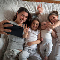 A family using FaceTime or some other video chat app in bed