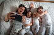 A family using FaceTime or some other video chat app in bed