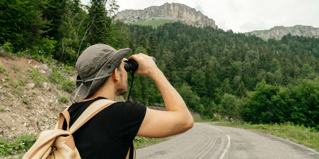 hiker looks through binoculars at nature