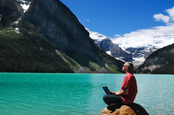 Man with laptop on lakeshore