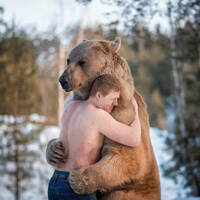 A guy hugging a bear. Presumably in Russia