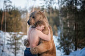 A guy hugging a bear. Presumably in Russia