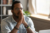 twentysomething man shows signs of huge relief, clasps hands together and closes eyes