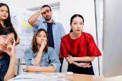 Five people in an office looking disappointed at a computer screen