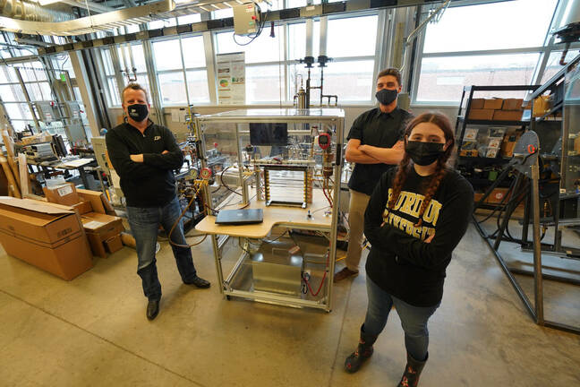 Testing liquid flooding in the fridge experiment. Purdue researchers Eckhard Groll (left), Leon Brendel and Paige Beck stand next to the experiment