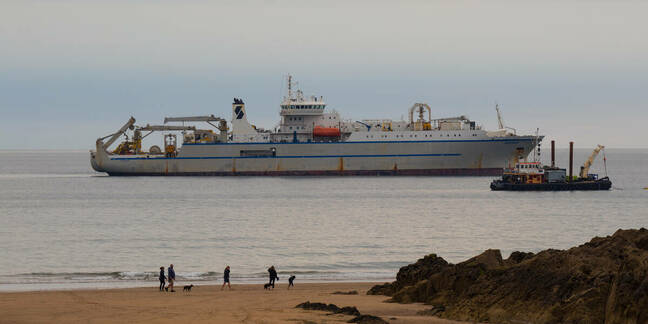 Bude, Cornwall, UK - July 2 2021: Cable laying ship with support vessel near the coast waiting to complete the undersea cable (grace hopper) project.