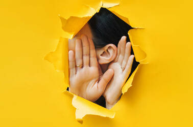 Someone listening through a hole ripped in a paper wall