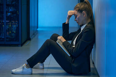 A datacenter worker sitting down looking dejected