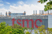tsmc sign in huge letters on a foundry in Taichung City with blue skies in the background and green trees in the foreground shot during summer