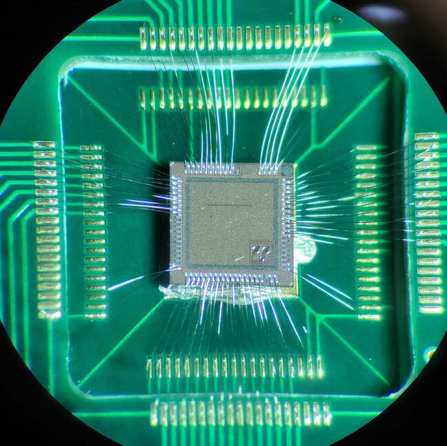 The Bloomsbury chip down a microscope showing it with wire bonds to a PCB