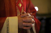 A Catholic priest in red prays