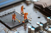 Small models of workmen cleaning up a computer motherboard with brushes