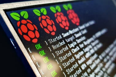 Close up of a screen showing an attached Raspberry Pi booting, with the logo in prominent view