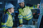 Workers in high-vis jackets standing at monitors in a factory or some form of critical infrastructure