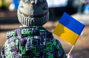 A kid in warm clothes holds a flag of Ukraine