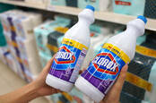 Someone holding up two bottles of Clorox in a store