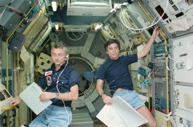 Astronaut Owen K. Garriott, STS-9 mission specialist, left, and Ulf Merbold, payload specialist. Dr Garriott holds in his left hand a data/log book for the solar spectrum experiment. Dr Merbold holds a map in his left hand for the monitoring of ground objectives of the metric camera.