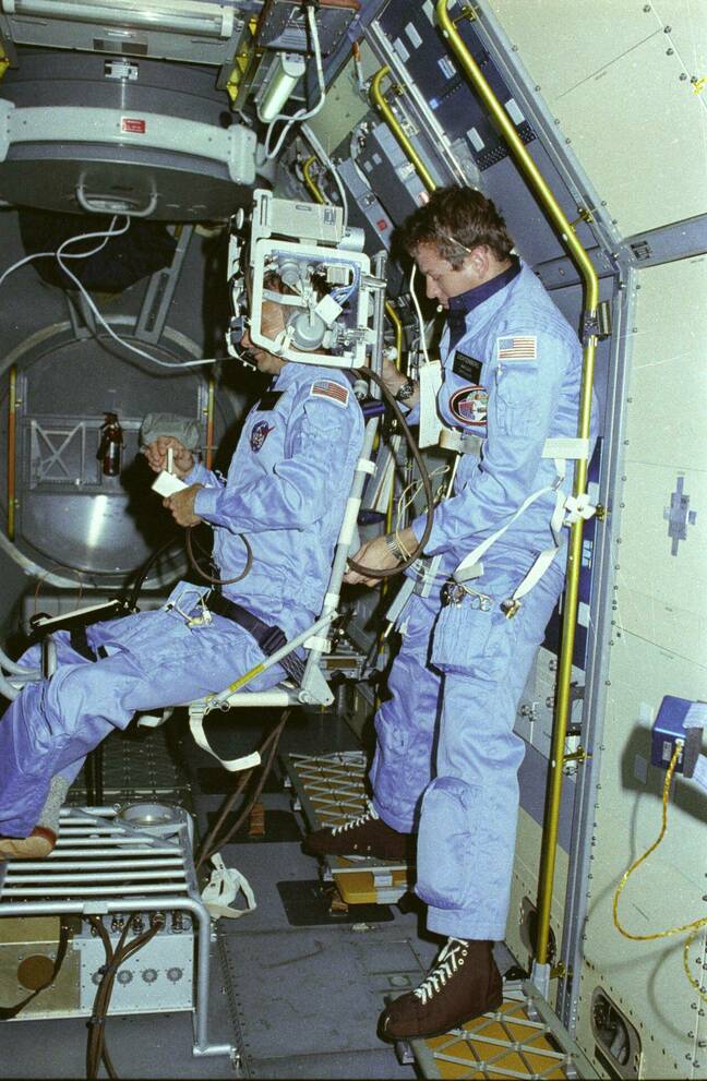 Astronauts Owen Garriott on the body restraint system and Byron Lichtenberg prepare for a Vestibular Experiment during the Spacelab-1 mission. The Vestibular Experiments in Space were the study of the interaction among the otoliths, semicircular canals, vision, and spinal reflexes in humans.