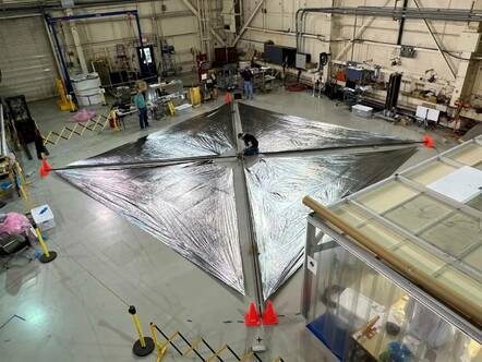 NASA Advanced Composite Solar Sail System unfurled on the floor with engineers working on it