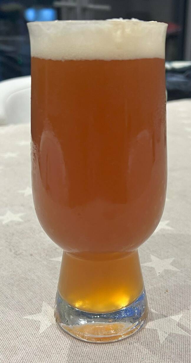 Beer A glass of hazy lager with a white foam head on a table