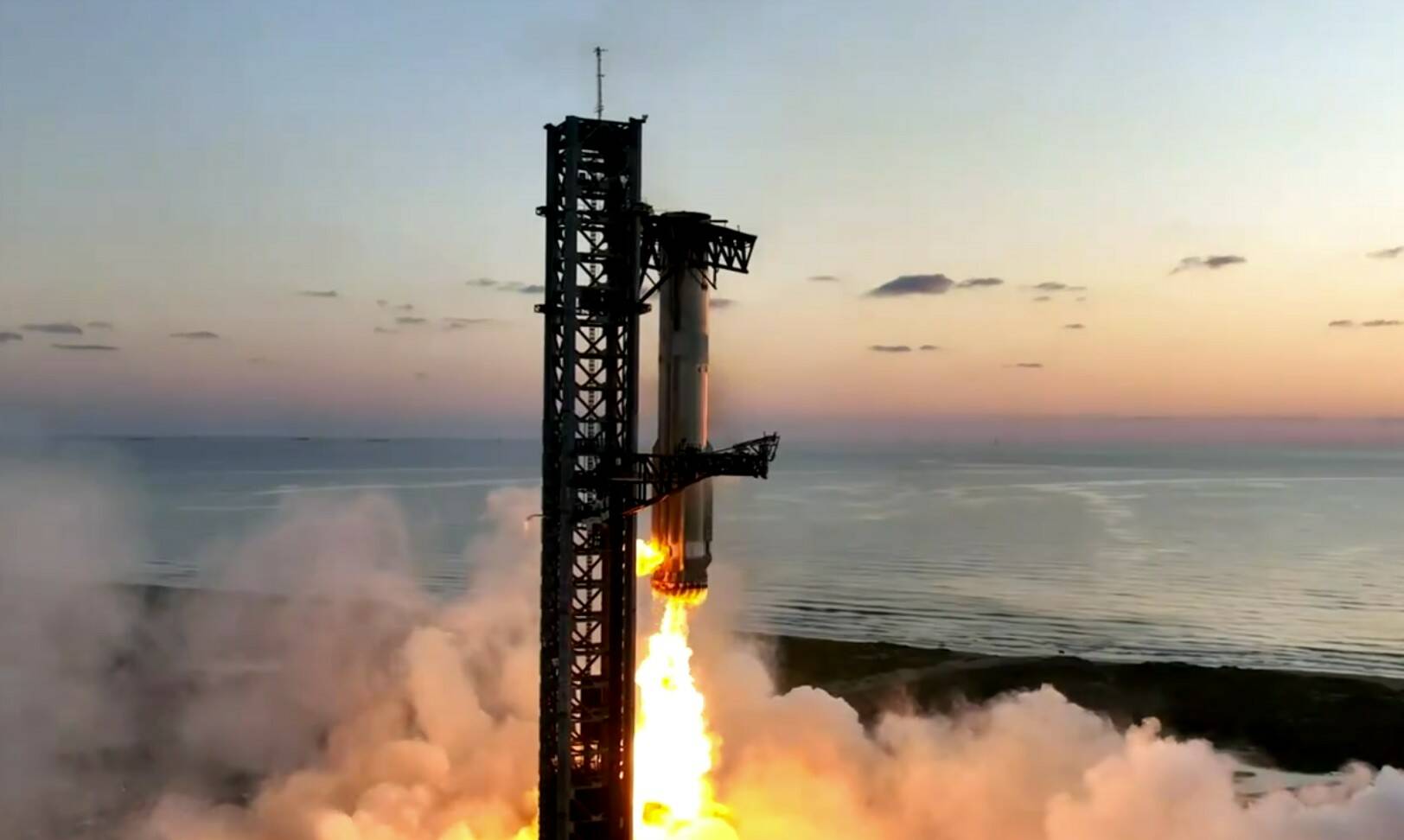 Mechanical chopsticks on the launch tower grab a returning rocket and Starship splashes down on target